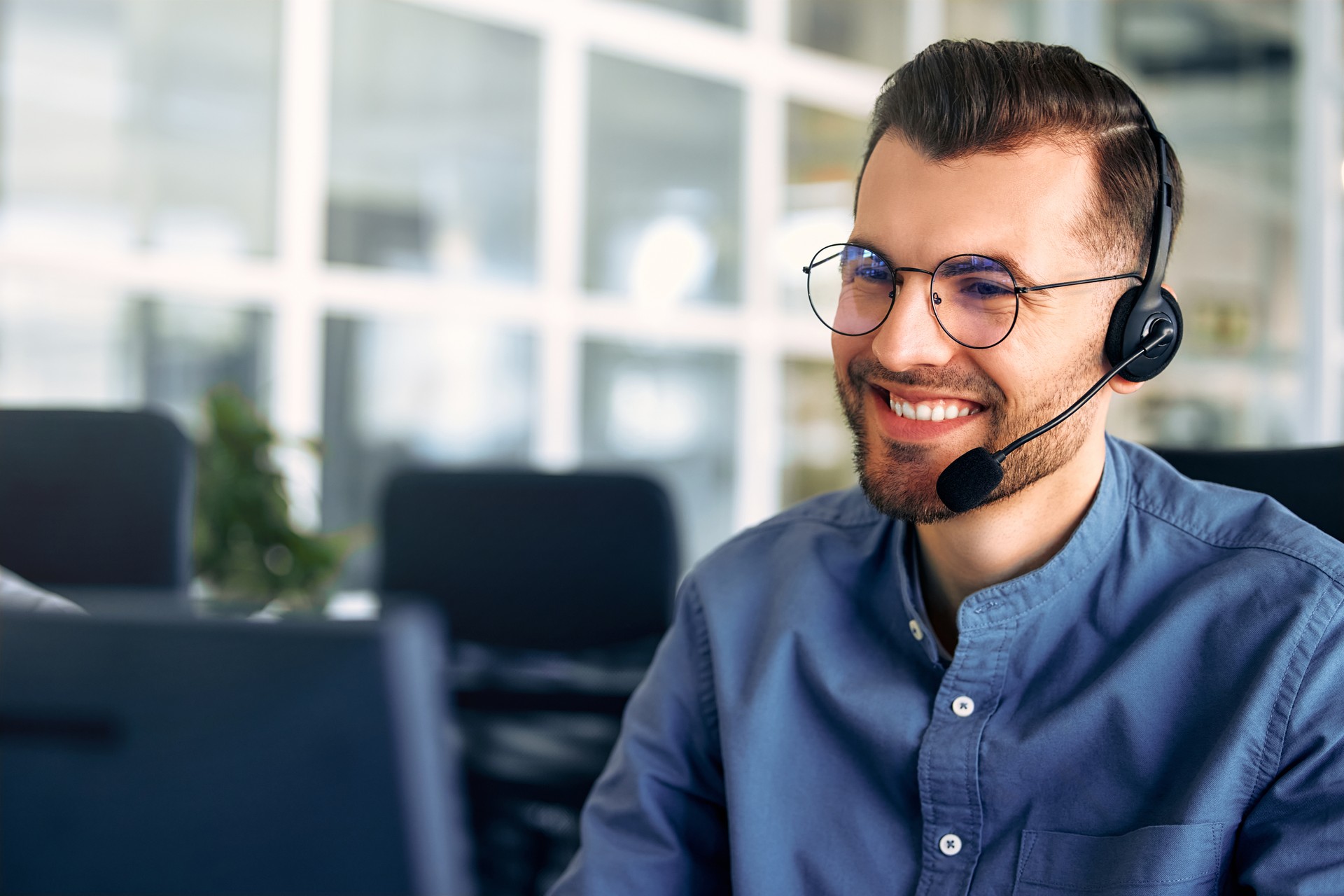 Ein Callcenter-Mitarbeiter sitzt im Büro an einem Laptop.