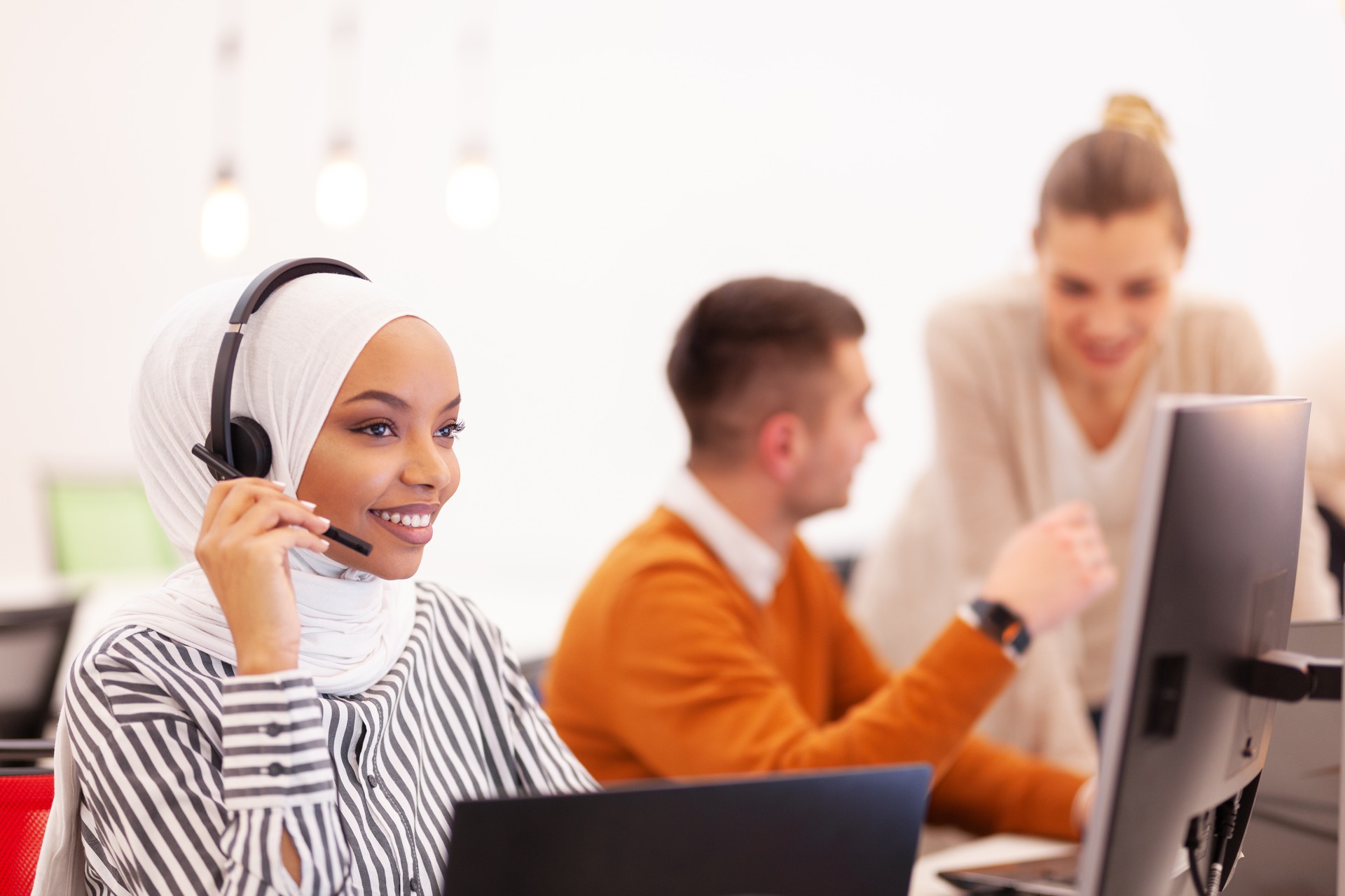 Afroamerikanisches muslimisches Mädchen mit Hijab und Headset in einem modernen Büro. Kundenservice Call Center