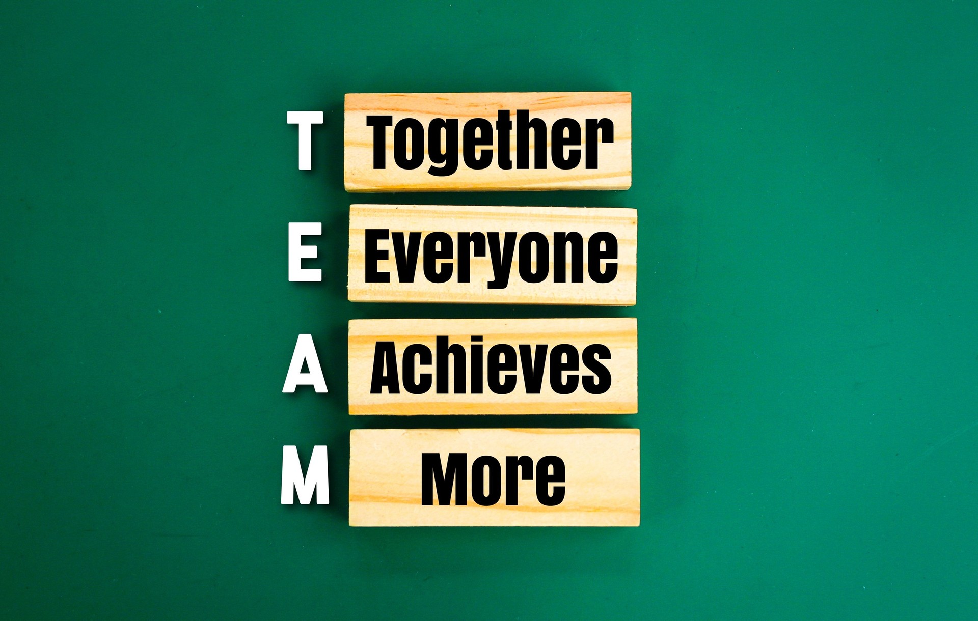 arrangement of wood with the word TEAM and the meaning of team. Together Everyone Achieves More